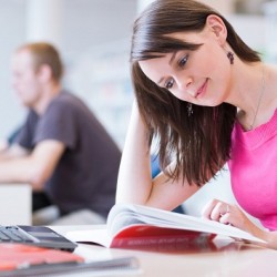 In the library - pretty female student with laptop and books