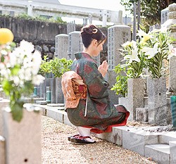 Japan, Kyoto, woman in kimono praying in cemetery