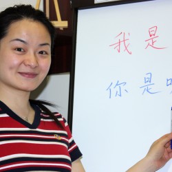 chinese teacher points on the blackboard in the classroom